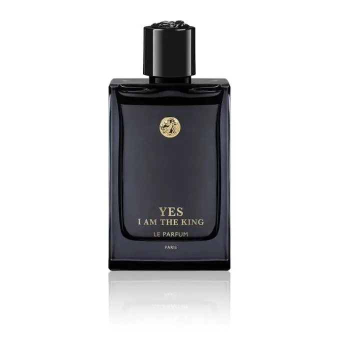 Flacon de parfum noir avec un bouchon noir, portant l'inscription dorée "YES I AM THE KING LE PARFUM PARIS" et un emblème doré.