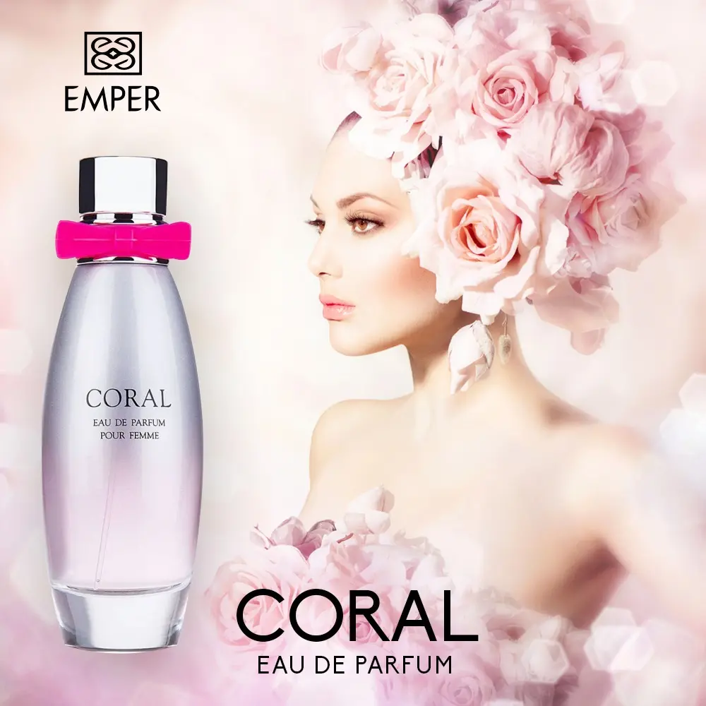 Flacon de parfum “Coral” d’Emper devant des roses pâles.