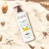 Flacon de lait corporel hydratant Evoluderm Monoi à la Folie sur du sable avec des coquillages et une étoile de mer.