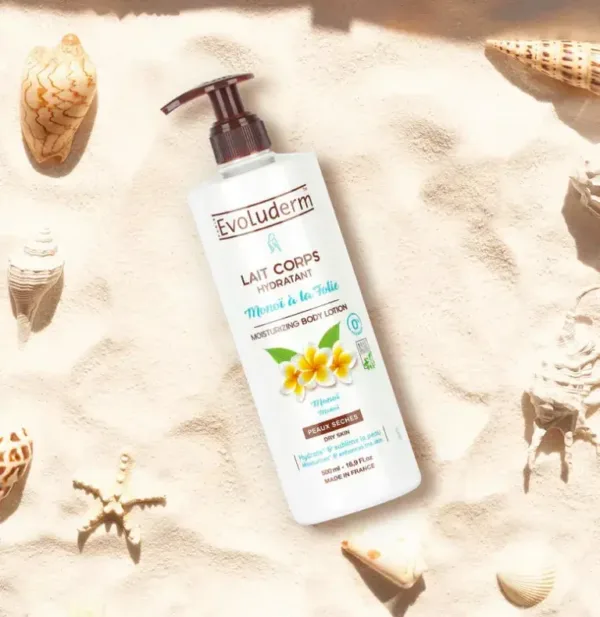 Flacon de lait corporel hydratant Evoluderm Monoi à la Folie sur du sable avec des coquillages et une étoile de mer.