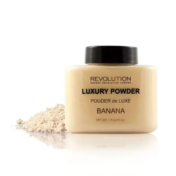 Poudre de luxe Revolution Banana, 42g, pour un teint parfait. Poudre libre avec bouchon noir, posée à côté d'un peu de poudre.