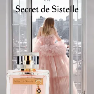 Parfum Secret de Sistelle devant fenêtre ouverte avec vue sur la ville et personne en robe rose, flacon avec clé dorée.