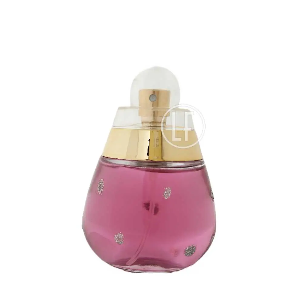 Flacon de parfum avec liquide rose et motifs floraux argentés, bouchon doré.