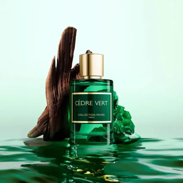 Flacon de parfum vert “CÈDRE VERT” avec bois et cristal sur une surface réfléchissante.