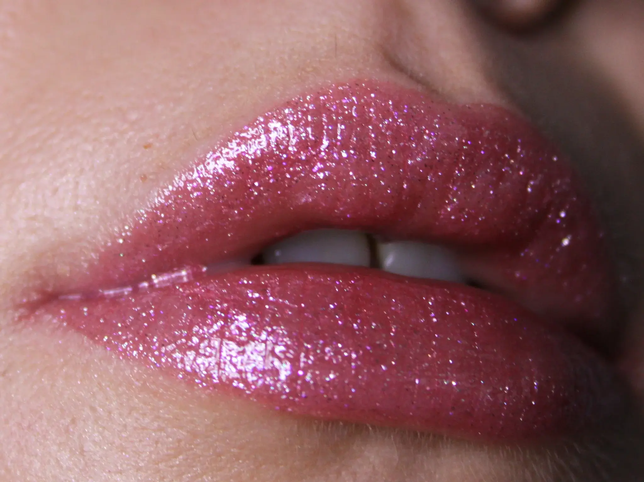 Lèvres avec du brillant à lèvres rose scintillant, montrant une texture lisse et brillante avec des reflets lumineux.